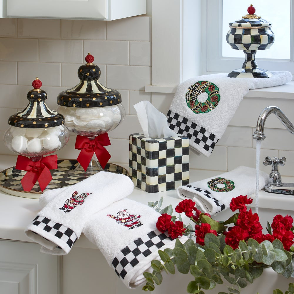 Decorative kitchen towels and accessories with black and white checkered patterns and red accents on a kitchen counter.