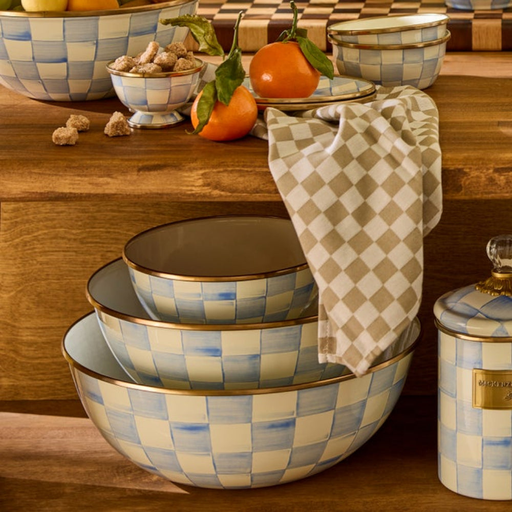 Set of checkered sky check ceramic bowls on a wooden surface with a towel draped over them and other sky check decor pieces on wooden display 