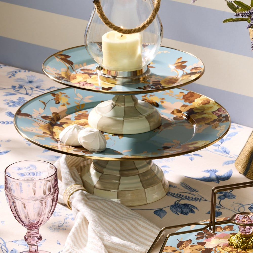 Two-tiered decorative stand with floral patterns on a table setting.