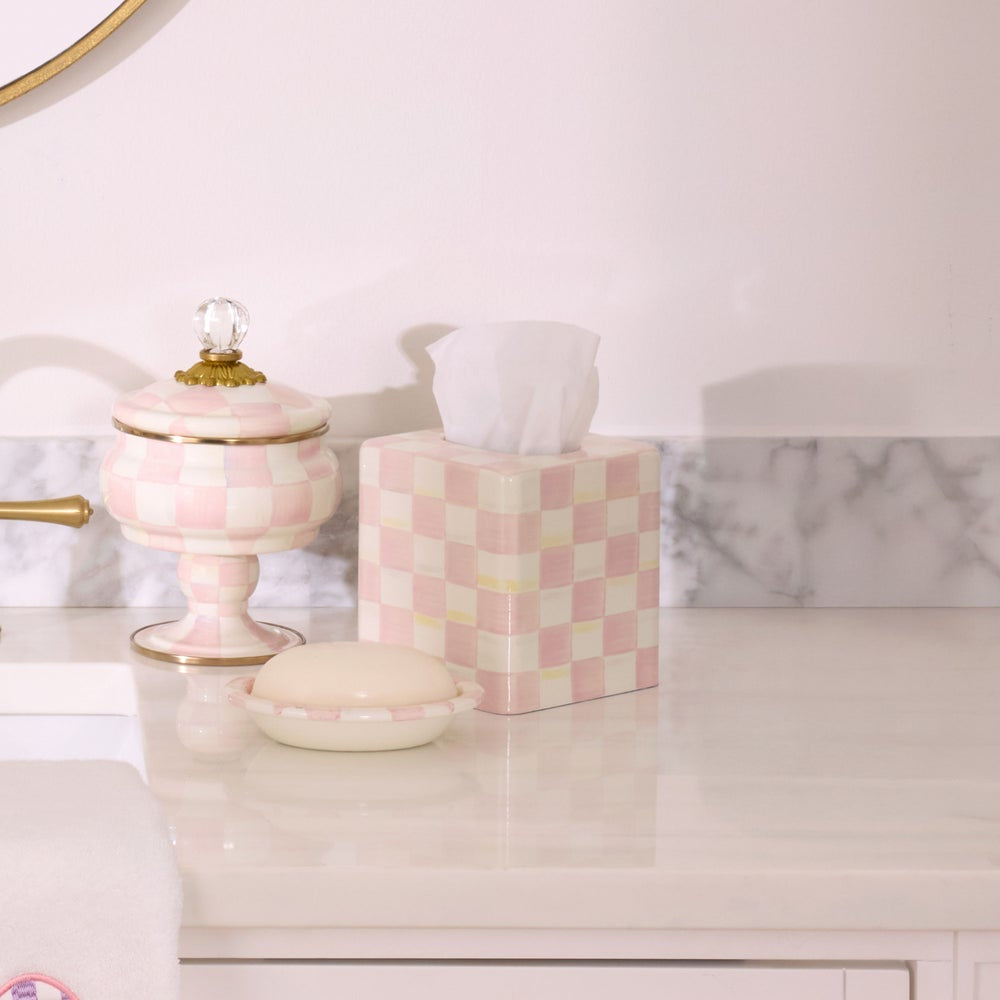 Checkered pink and white tissue box on a bathroom counter with decorative jar and soap.