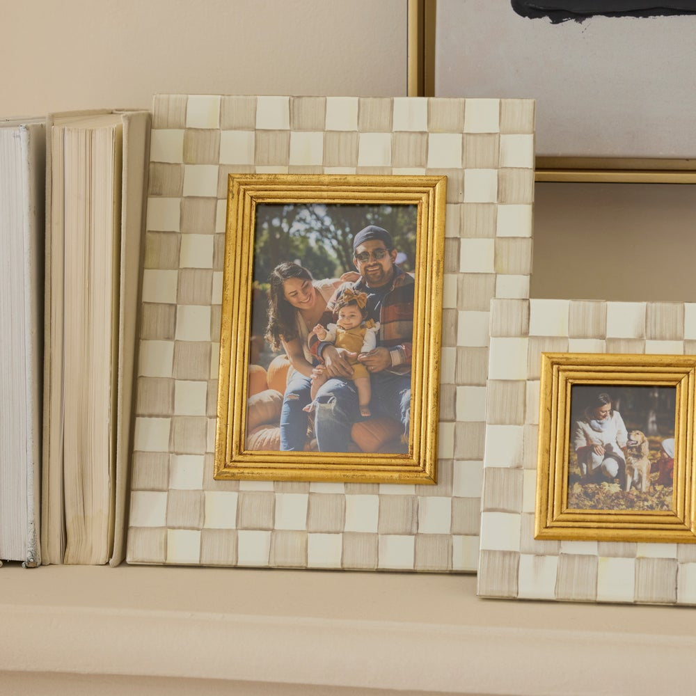 Two gold-framed pictures on a decorative wall with a tiled background