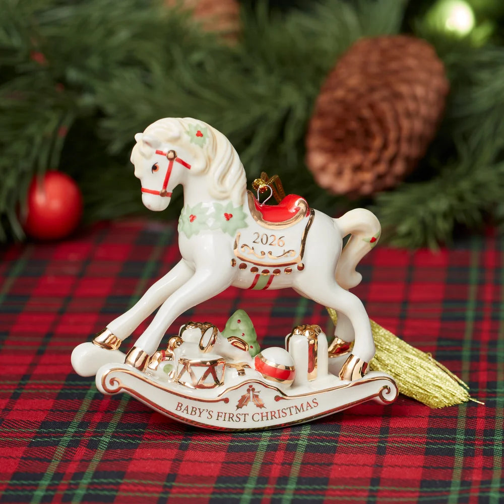 Decorative rocking horse ornament with 'Baby's First Christmas' and '2026' text on a plaid fabric background.