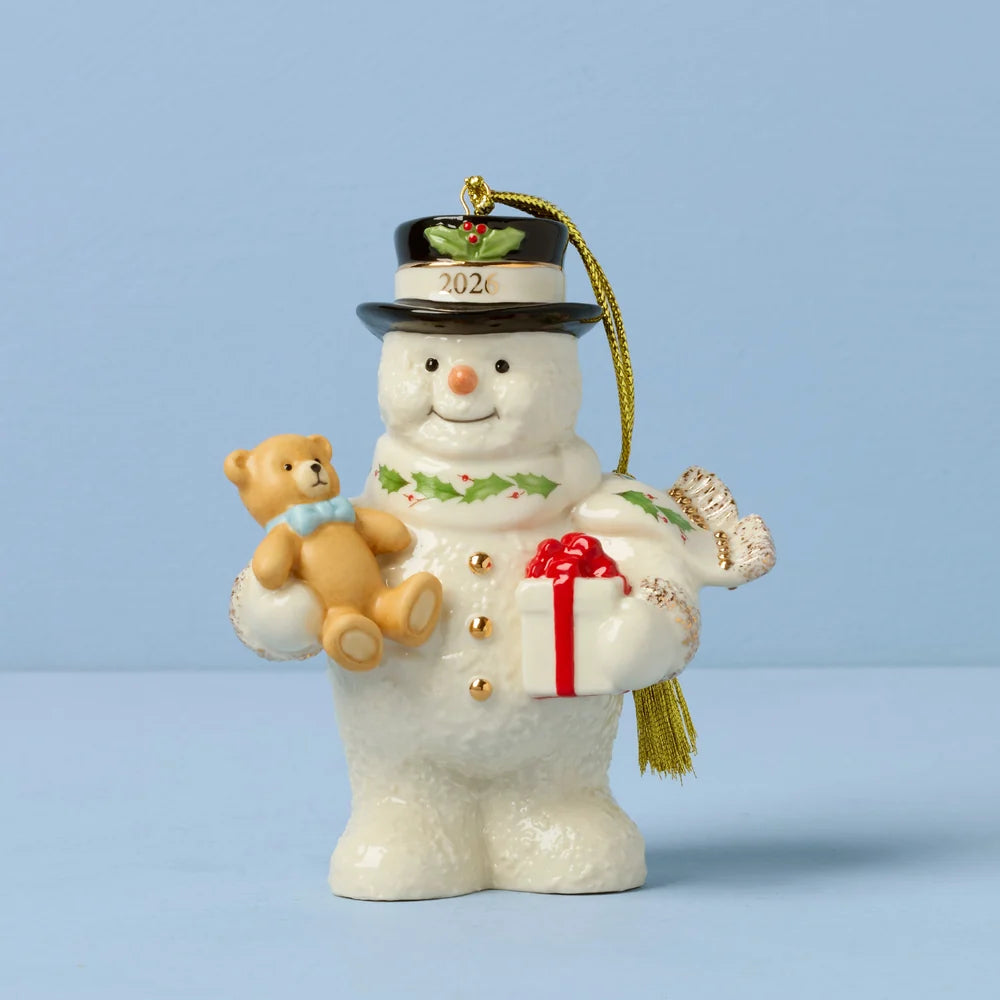 Decorative snowman ornament with a teddy bear, gift, and top hat on a light blue background