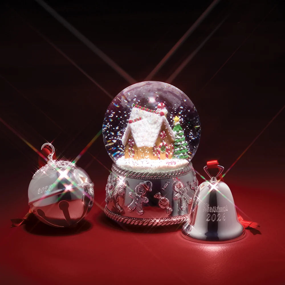 A collection of a silverplated snow globe, silverplated jingle bell ornament, and silverplated bell ornament