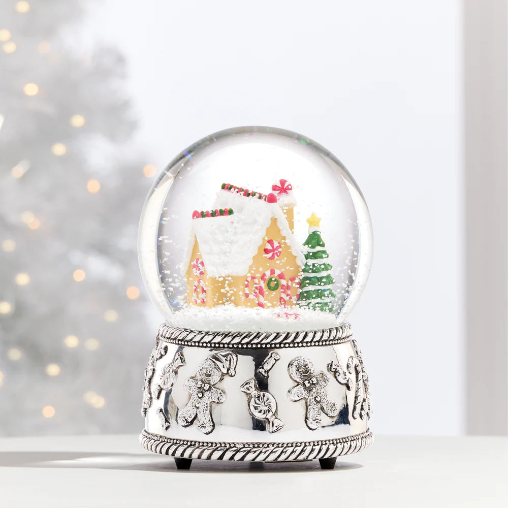 Silver plate snow globe with a gingerbread house inside, shown on a light grey background