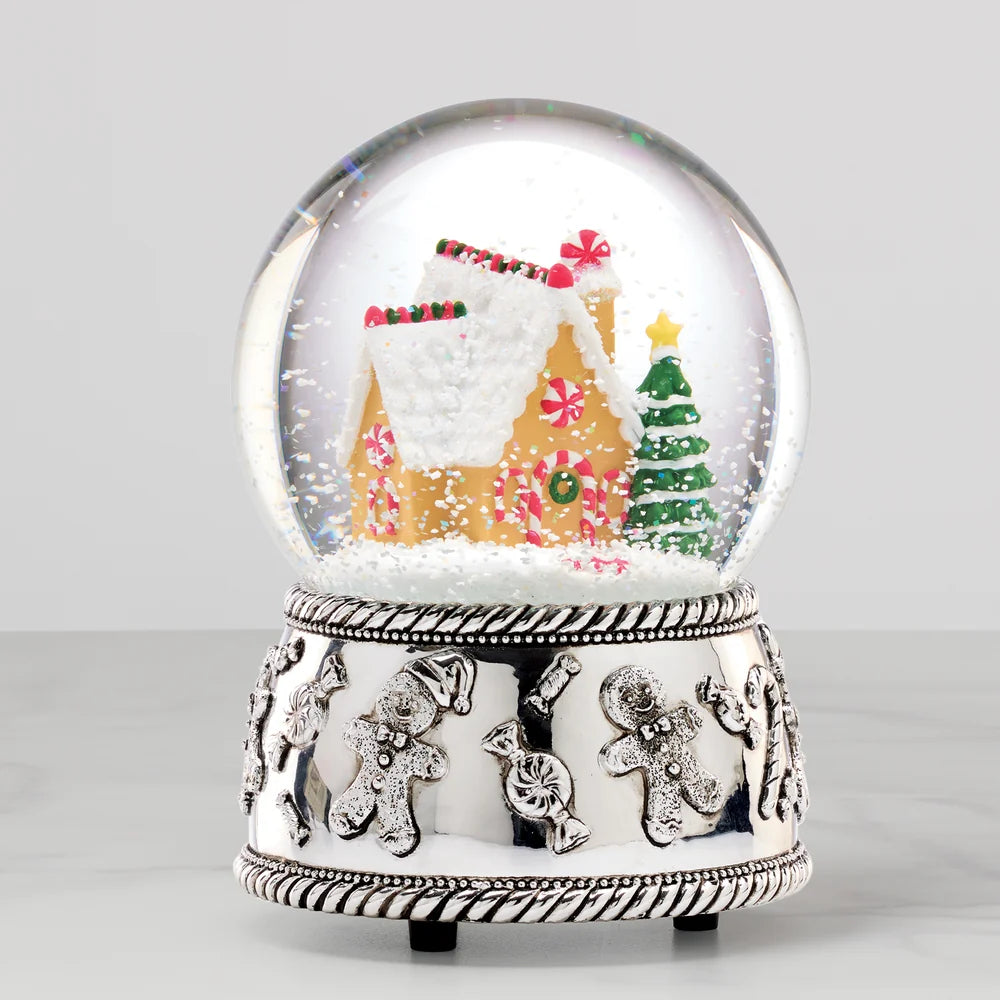 Silver plate snow globe with a gingerbread house inside, shown on a light grey background
