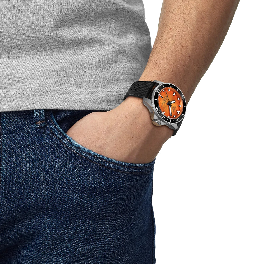 Person wearing a watch with an orange face and black strap, with a gray shirt and blue jeans.