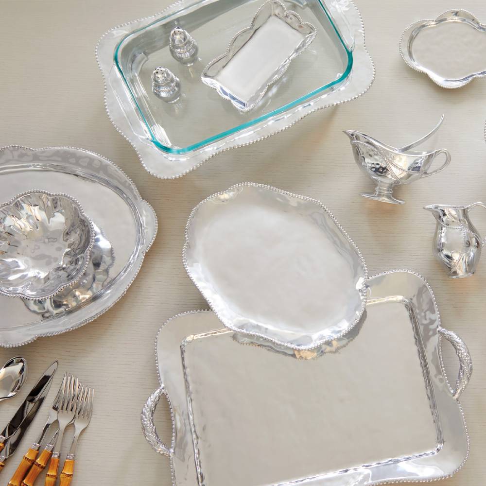 Collection of silver platters, bowls, and serving pieces on a light background