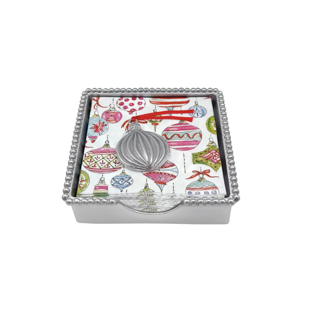 Beaded ornament napkin box with ornament themed napkins and weight on a white backround. 