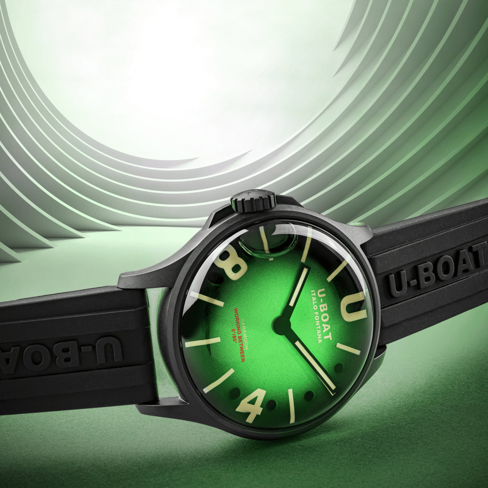 A wristwatch with a black rubber strap and case, featuring a bright green dial with large cream-colored numerals and hands. The strap has 'U-BOAT' embossed on it, and the dial has 'U-BOAT TIME DOOM' and 'JAPAN METER' text.