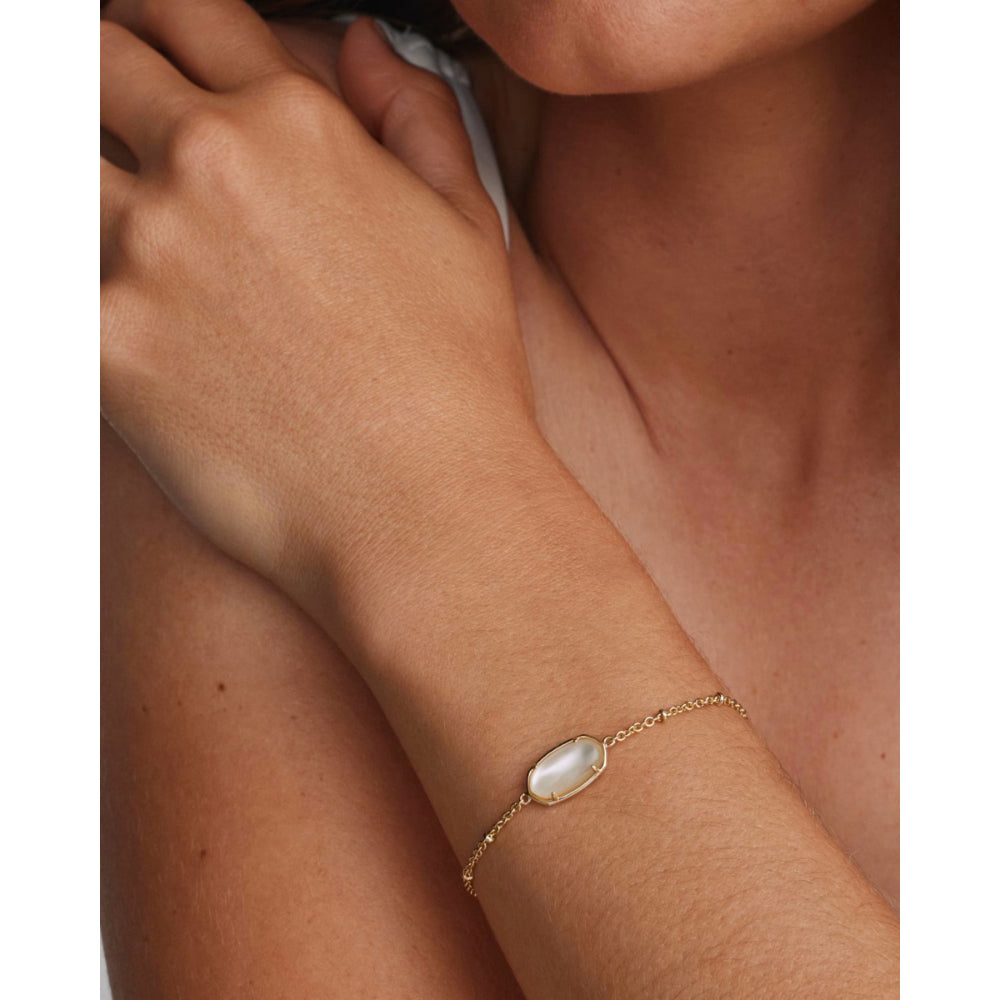 A delicate gold chain bracelet with an oval white mother-of-pearl centerpiece, shown worn on a model's wrist.