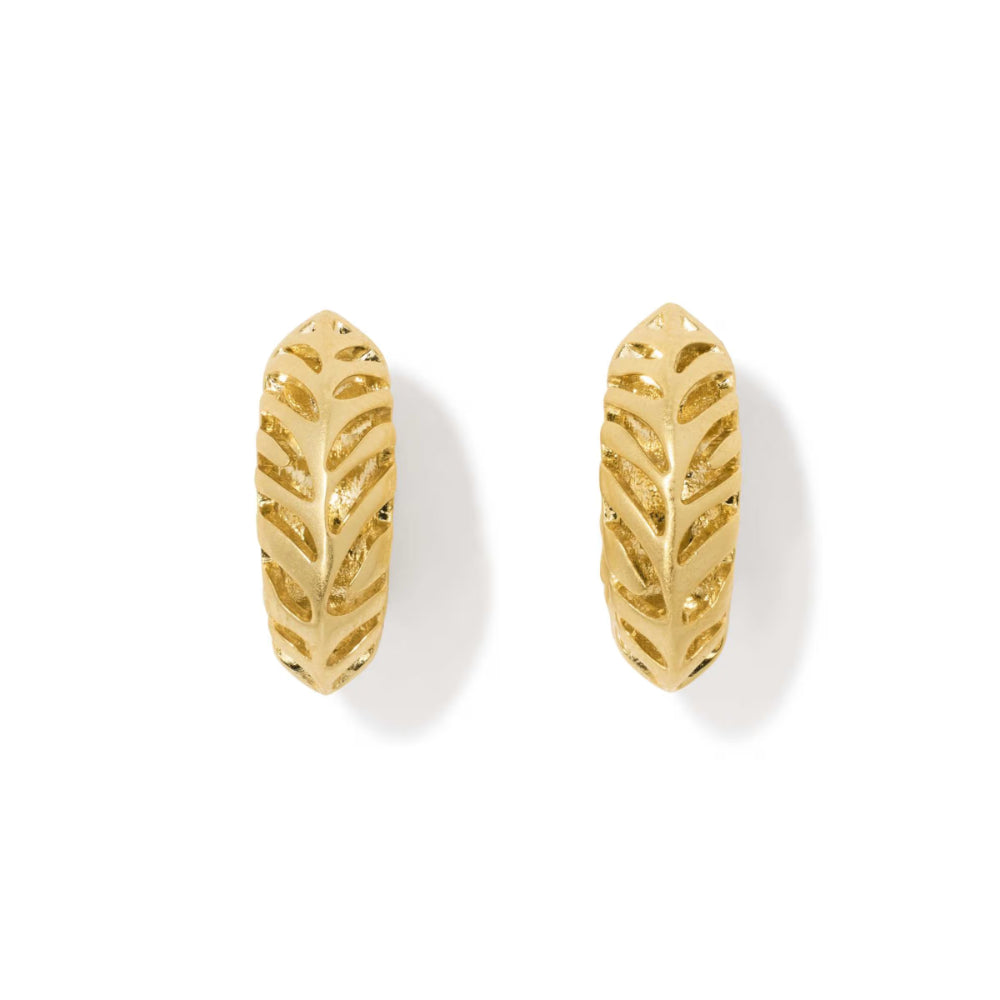A pair of gold huggie hoop earrings with a leaf cutout pattern, displayed on a clean white background with soft shadows.