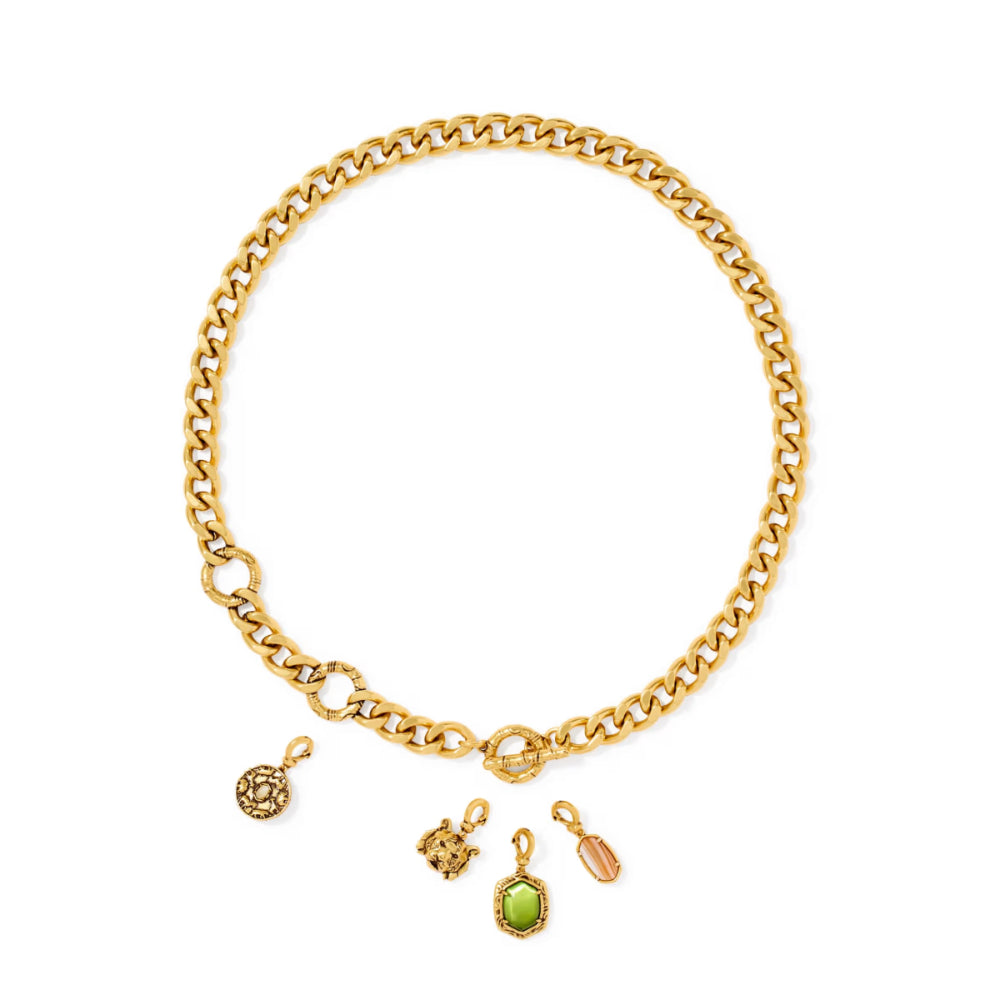A gold chain necklace with three dangling charms, including a green oval stone pendant, a small gold animal charm, and a gold key charm, displayed on a clean white background.