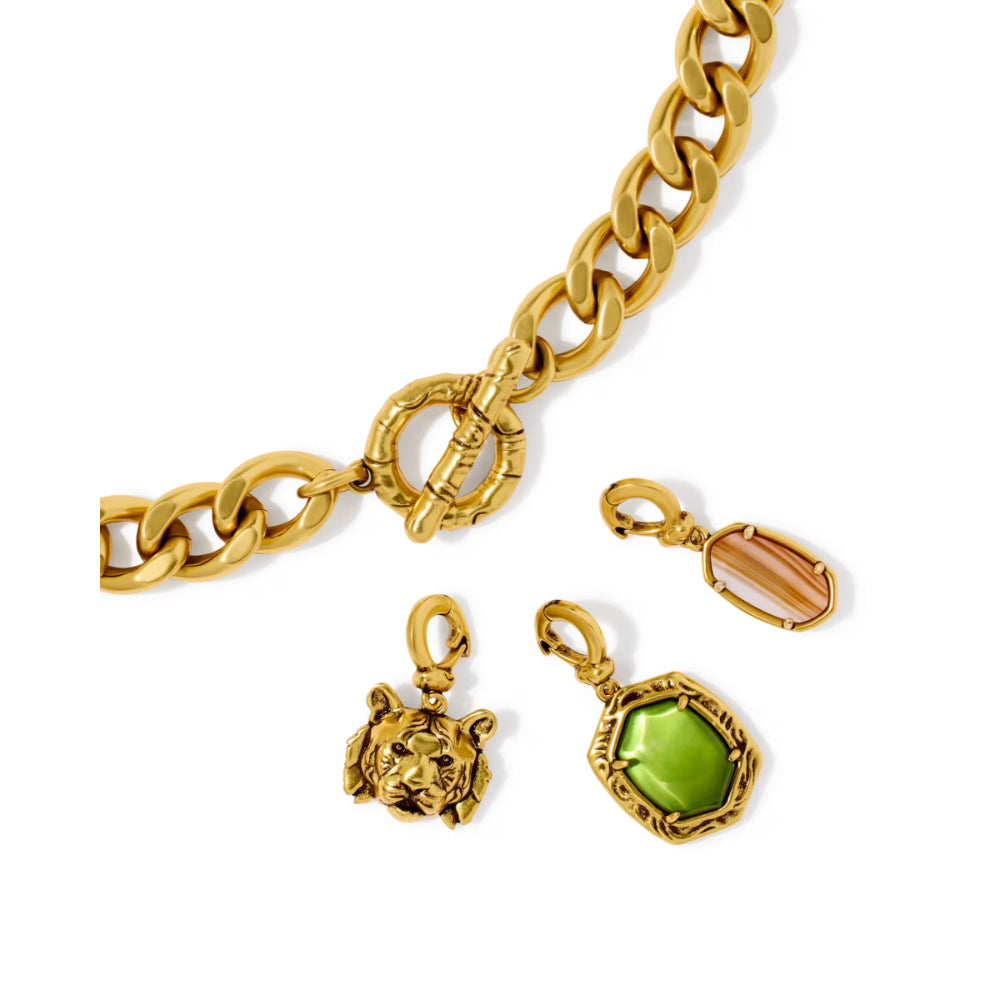 Gold-tone jewelry set featuring a chunky curb chain with a toggle clasp, a lion head pendant, an oval green gemstone pendant, and a smaller peach-colored oval gemstone pendant, displayed on a clean white background.