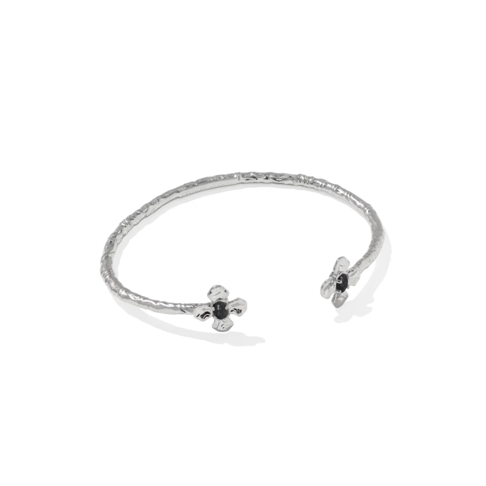 A textured silver open cuff bracelet with two small flower-like end details featuring dark gemstones, shown on a clean white background.
