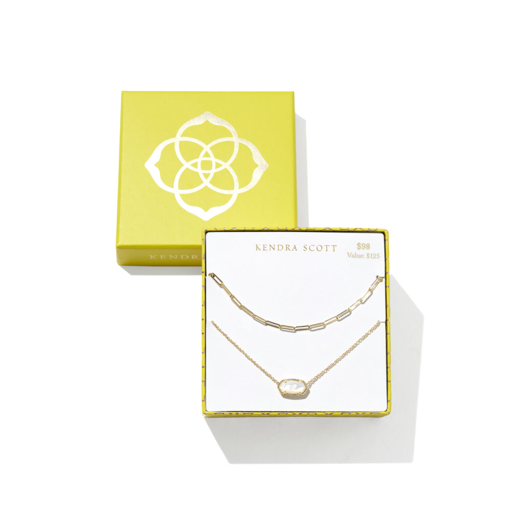 A gold double-layer necklace set by Kendra Scott, displayed in its white and yellow gift box alongside a larger yellow brand box on a clean white background.