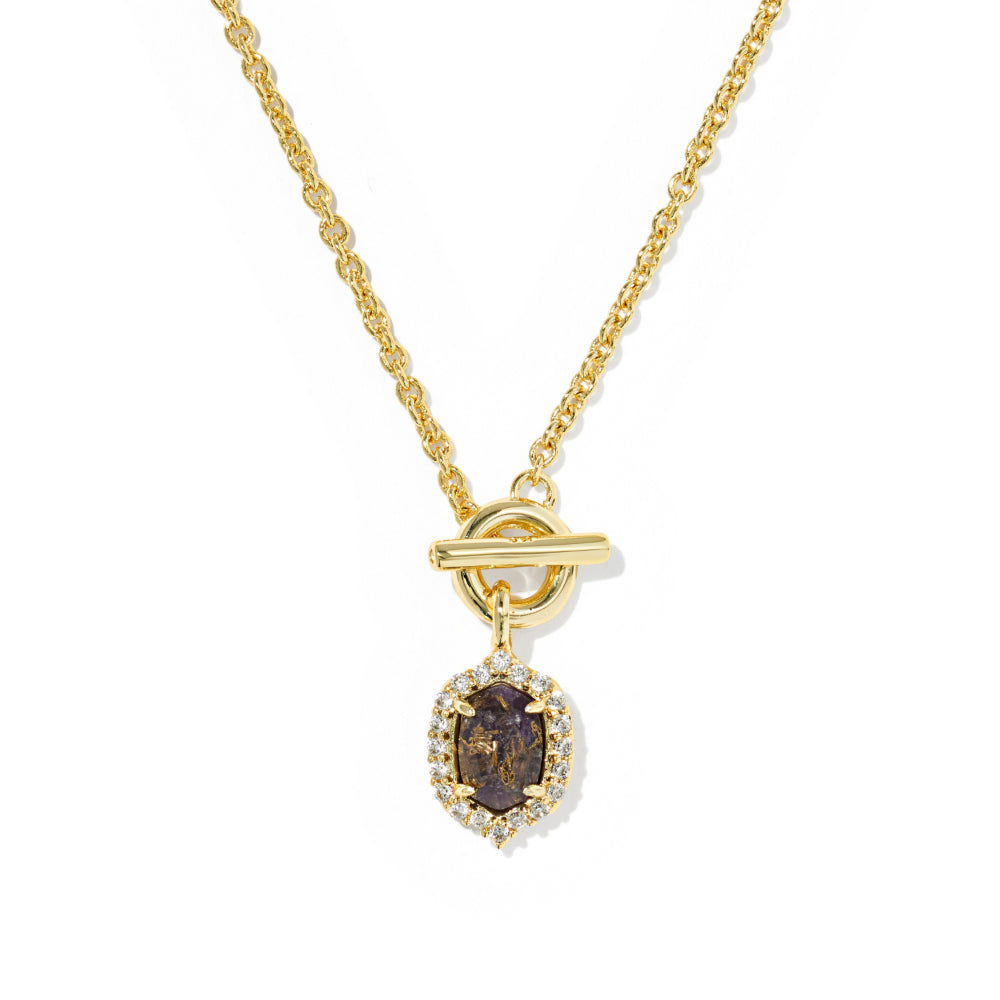 A gold chain necklace with a toggle clasp and a central oval pendant. The pendant features a dark brown gemstone surrounded by a halo of small clear stones, set against a plain white background.