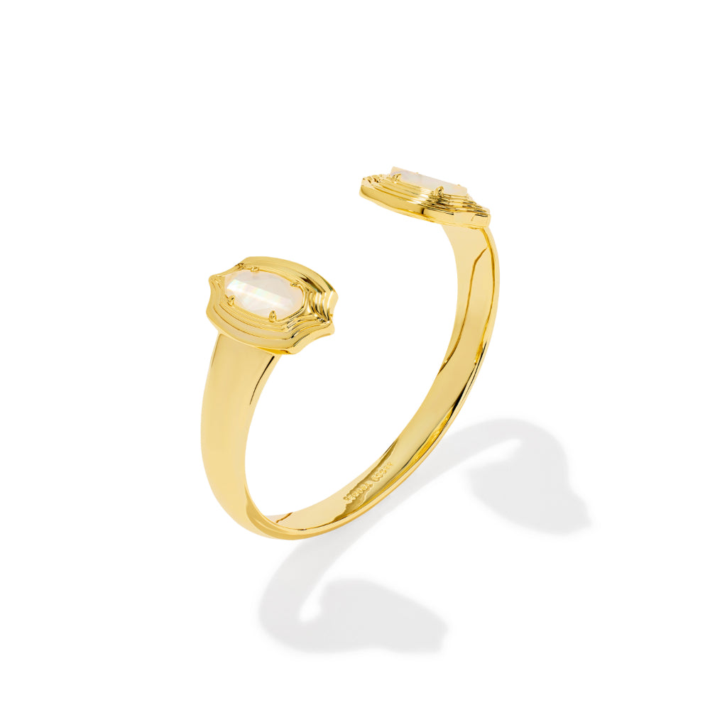 A gold open cuff ring featuring two oval-cut white gemstones, shown on a clean white background with a soft shadow.