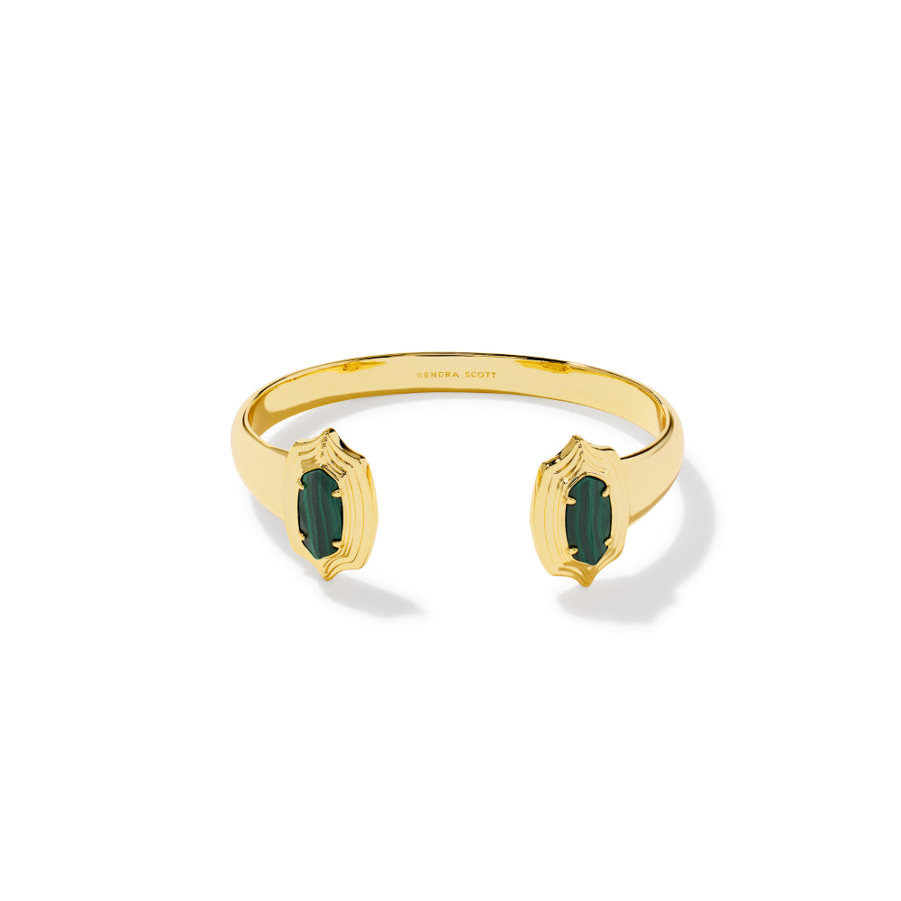 A gold open cuff bracelet with two emerald-cut green gemstone accents, shown on a clean white background.