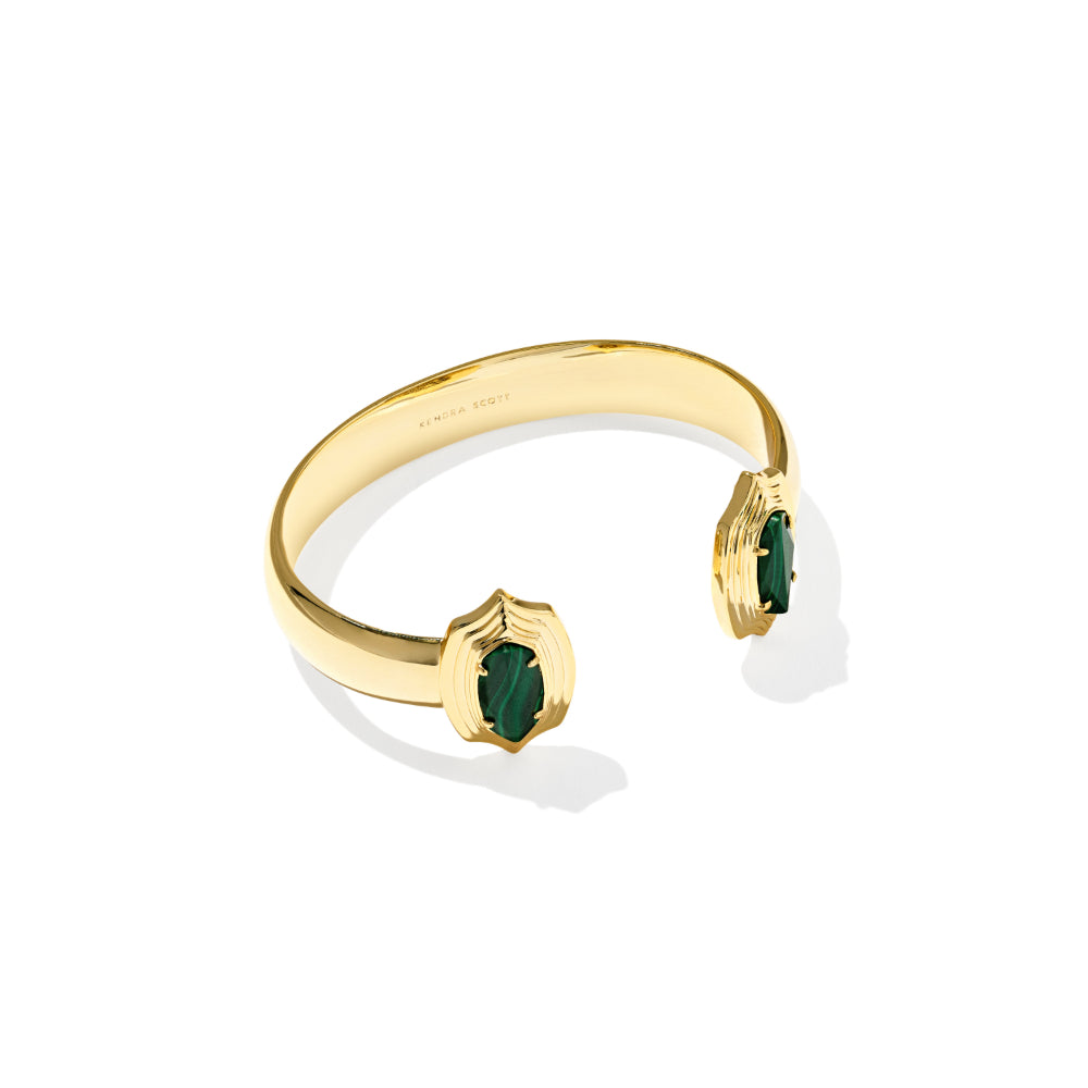 A gold open cuff bracelet with two shield-shaped settings holding deep green marquise-cut gemstones, shown on a clean white background.