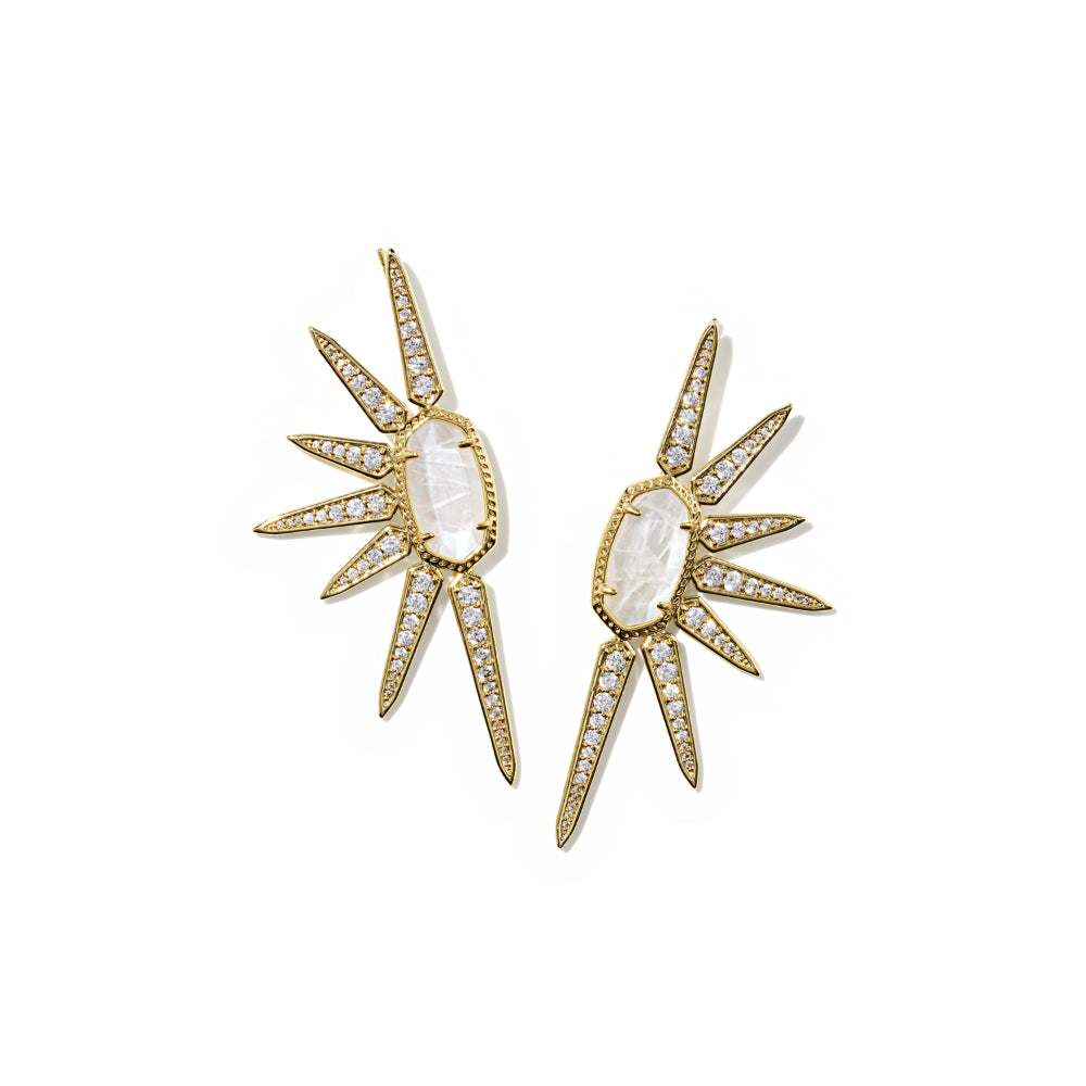 A pair of gold-toned statement earrings featuring a central oval moonstone surrounded by radiating starburst shapes paved with small clear stones, shown on a plain white background.