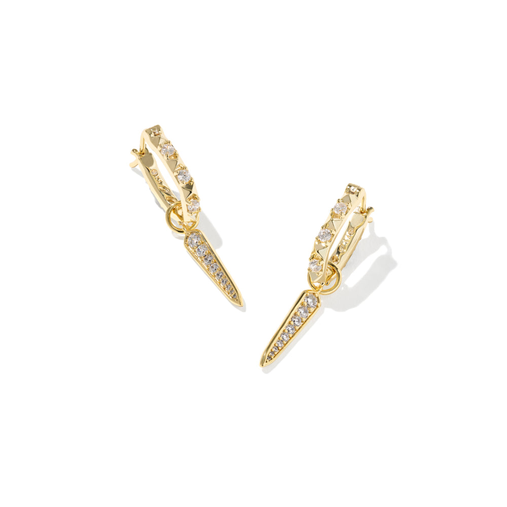 A pair of gold huggie hoop earrings with a dangling chevron spike design, both adorned with small clear pavé stones, shown on a clean white background with soft shadows.