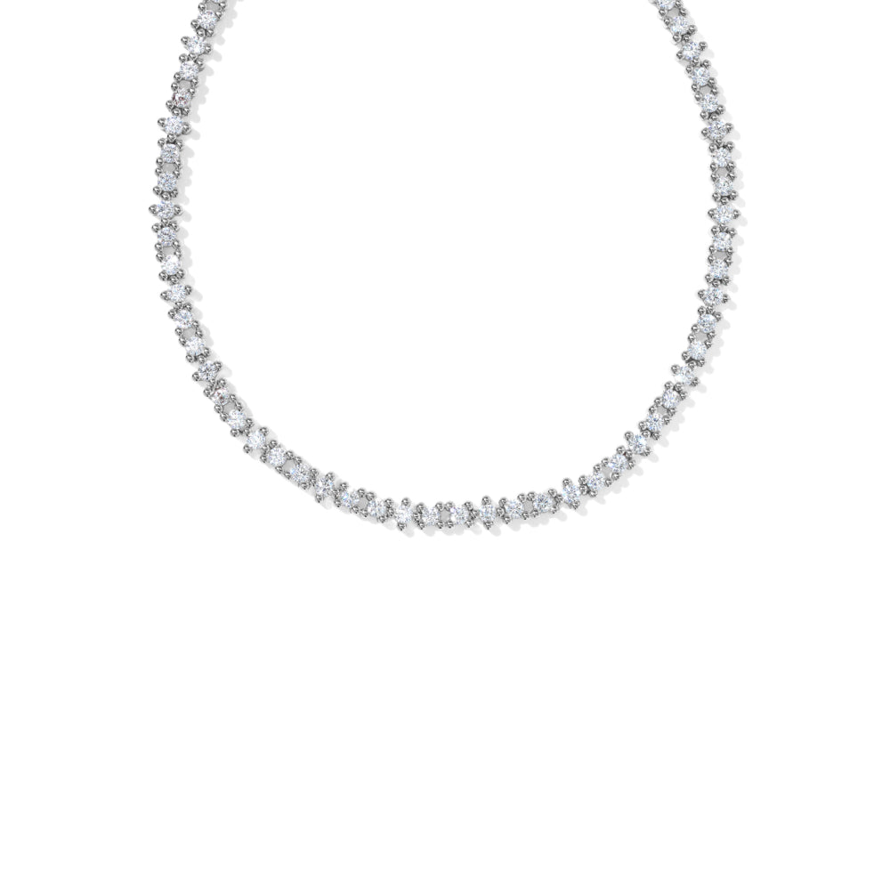 A delicate tennis necklace featuring small, closely-set round-cut clear gemstones in a silver-toned setting, photographed against a solid white background.