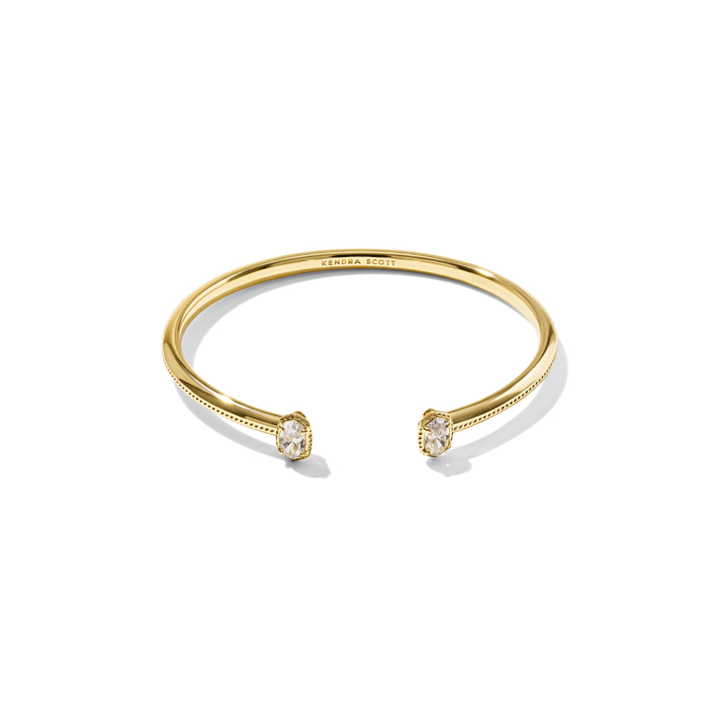 A gold open cuff bracelet with two bezel-set clear gemstones, shown on a clean white background. The inside of the band is engraved with 'TROYAN JEWEL'.