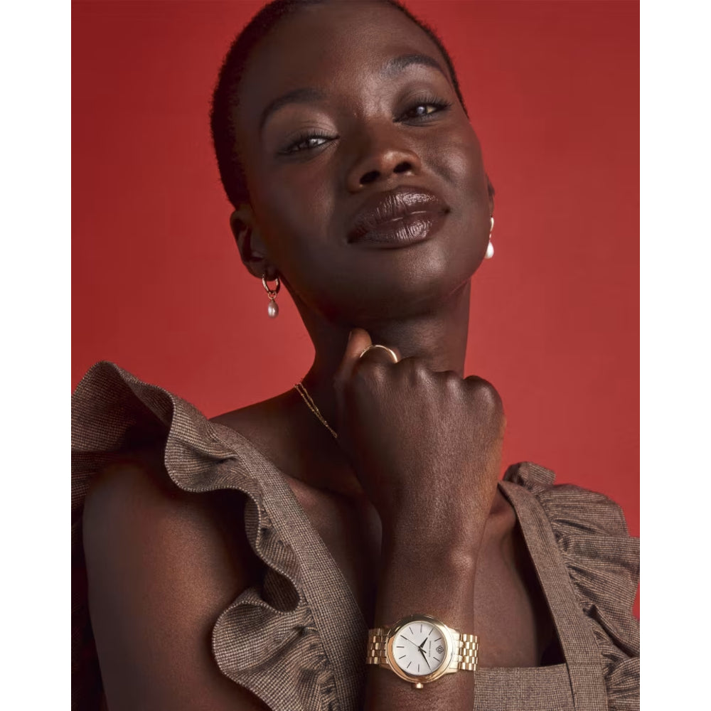 Woman wearing a gold watch on a red background