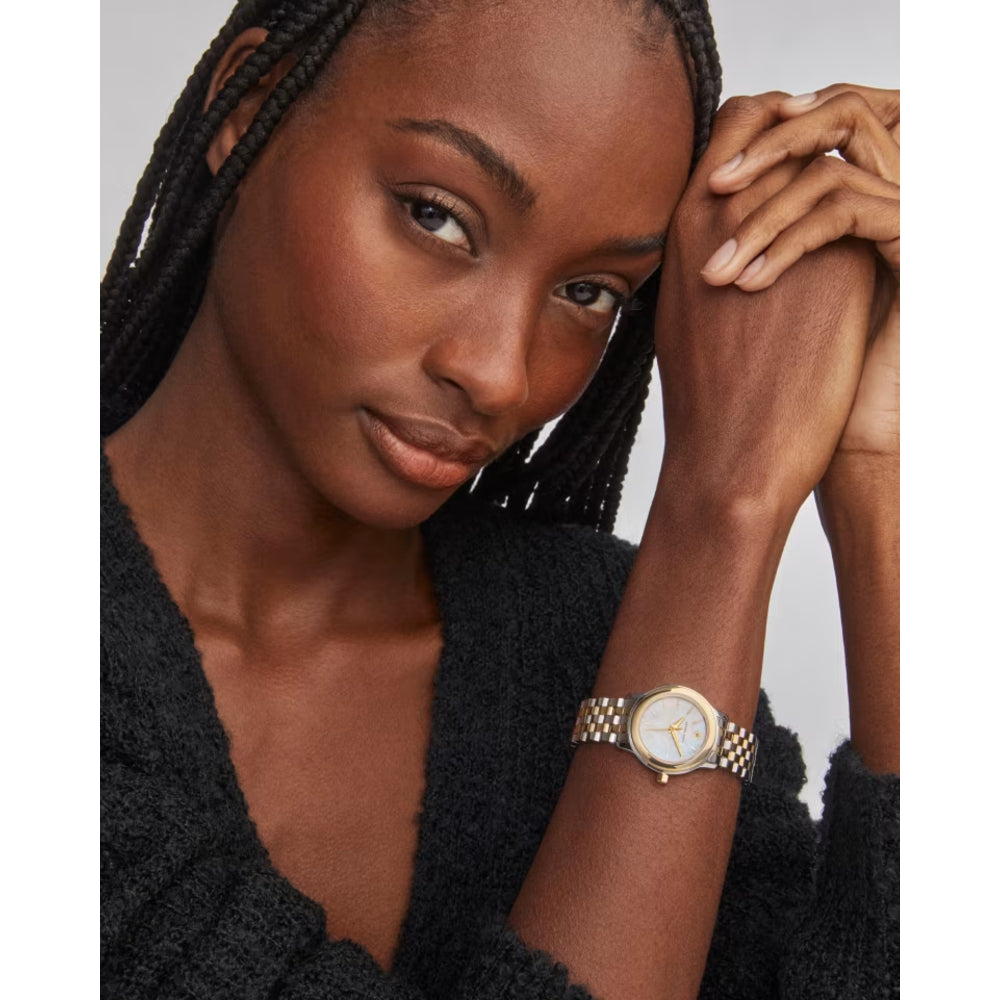 Woman wearing a gold watch with a neutral background