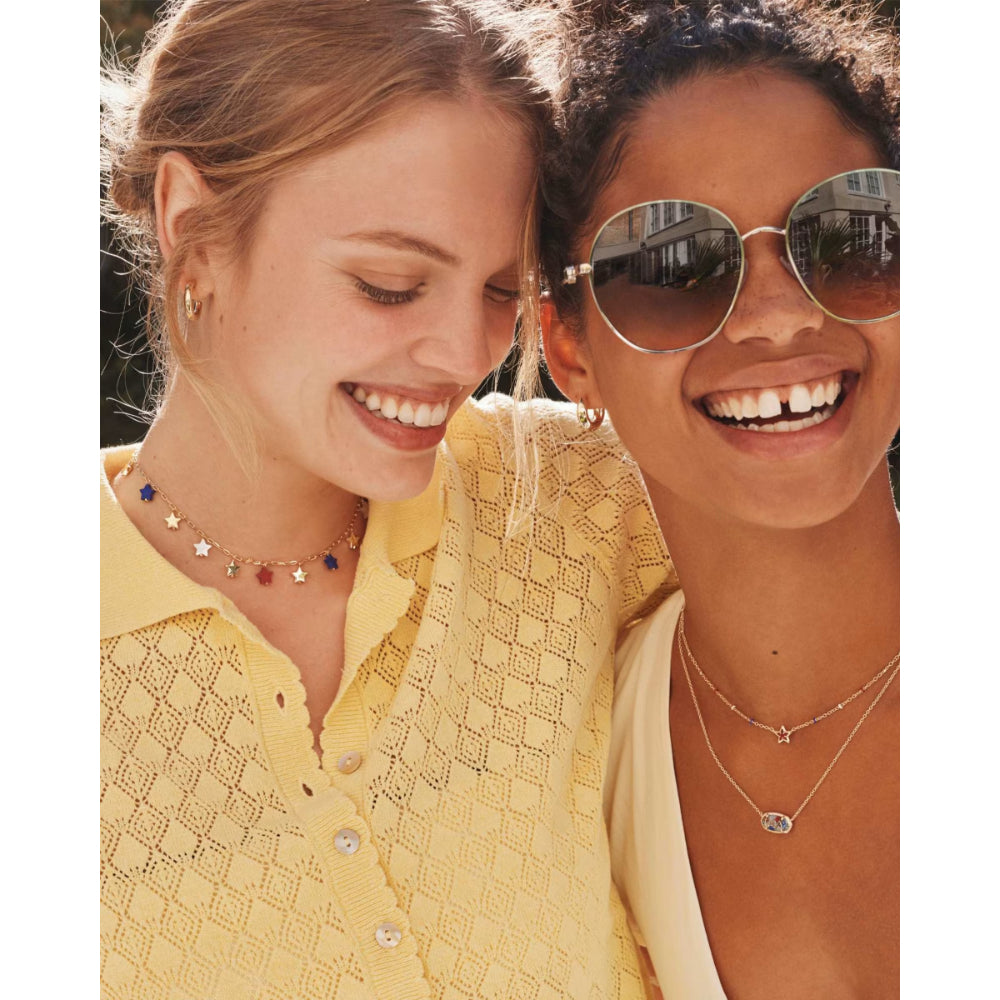 Two women smiling and wearing necklaces with a neutral background