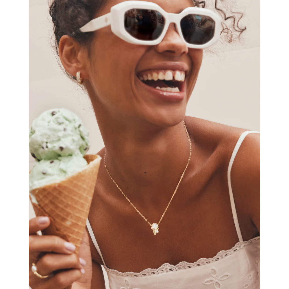 Woman wearing white sunglasses and holding a ice cream cone, smiling.