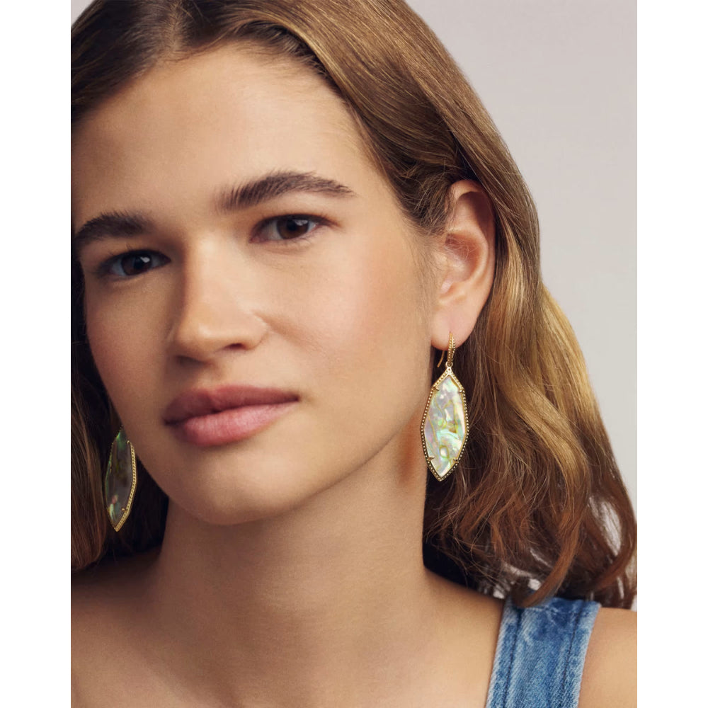 Close-up of a woman wearing gold earrings with a light background