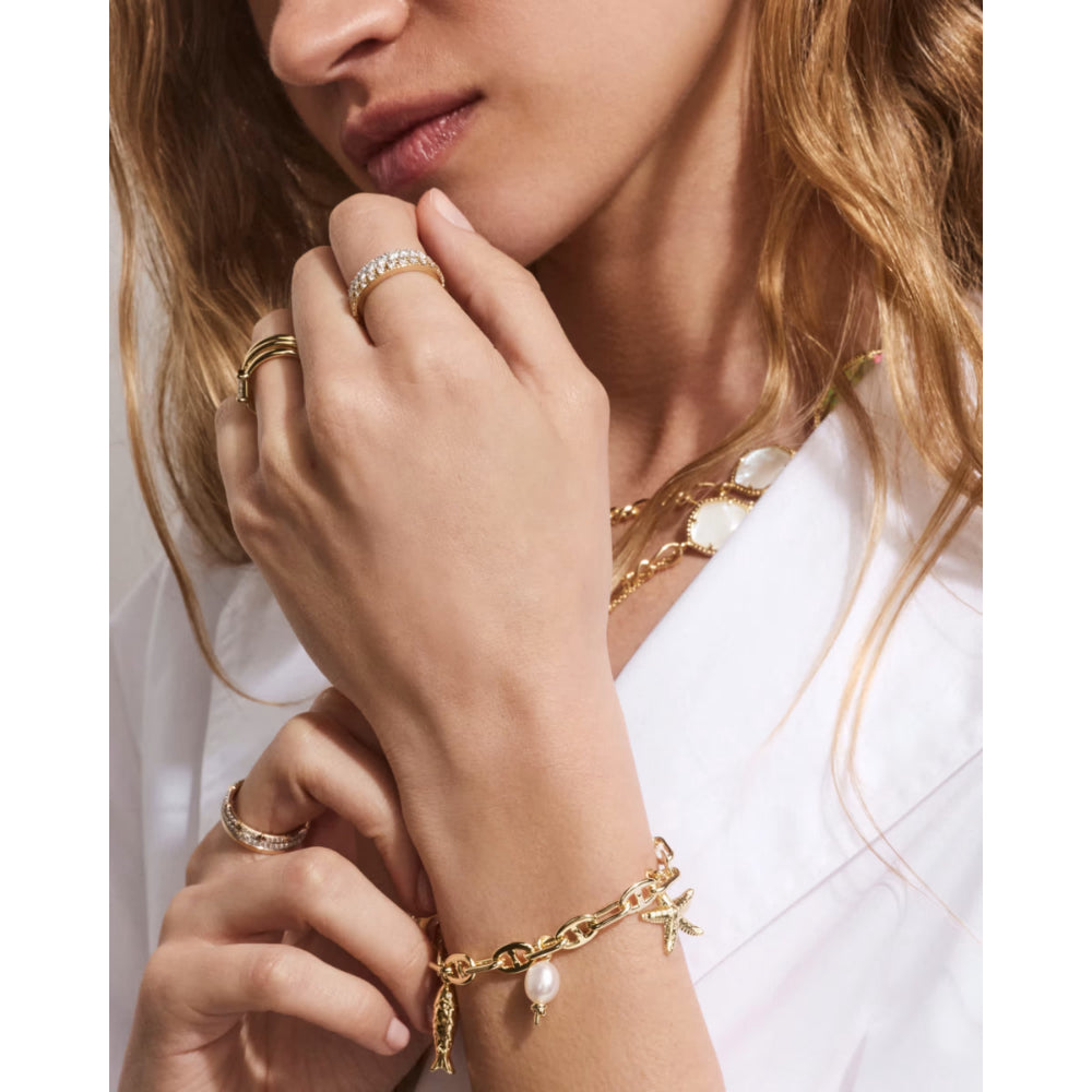 Close-up of a person wearing gold charm bracelet.