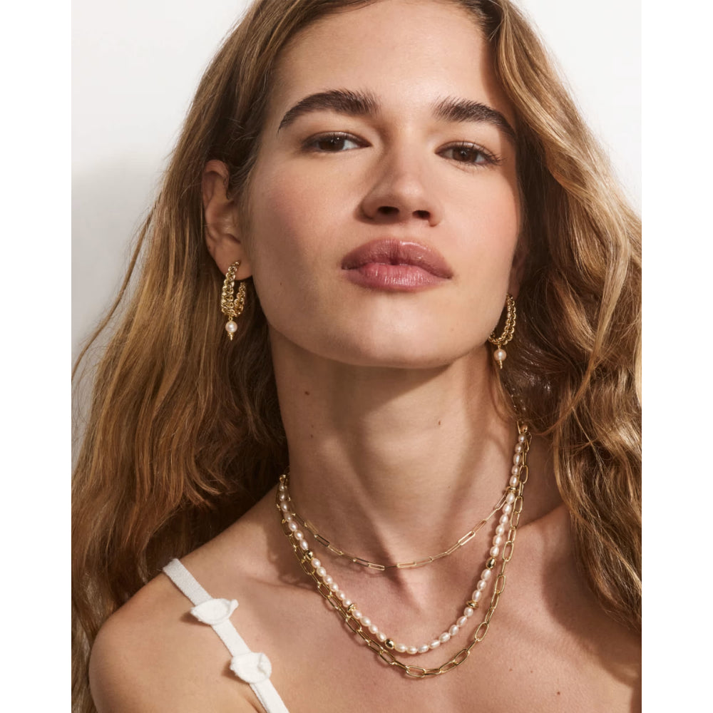 Woman wearing gold necklaces and earrings on a white background