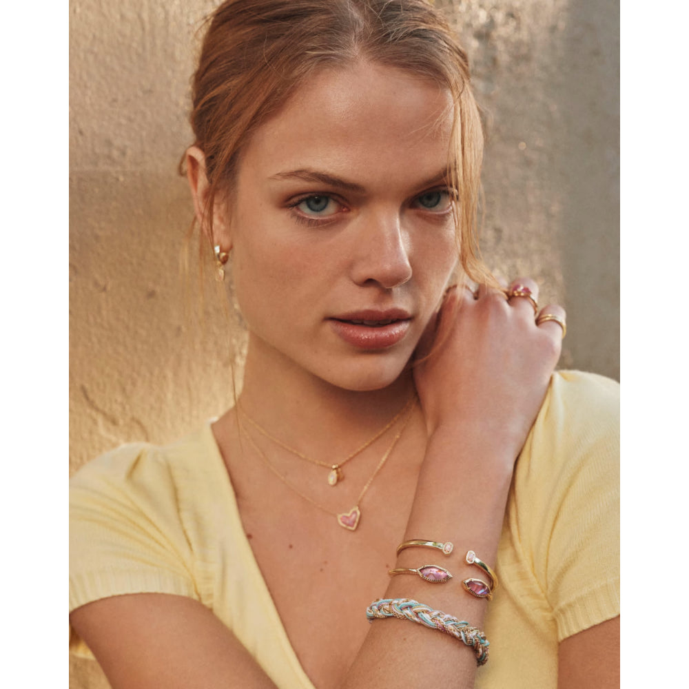 Woman wearing gold jewelry with a neutral background