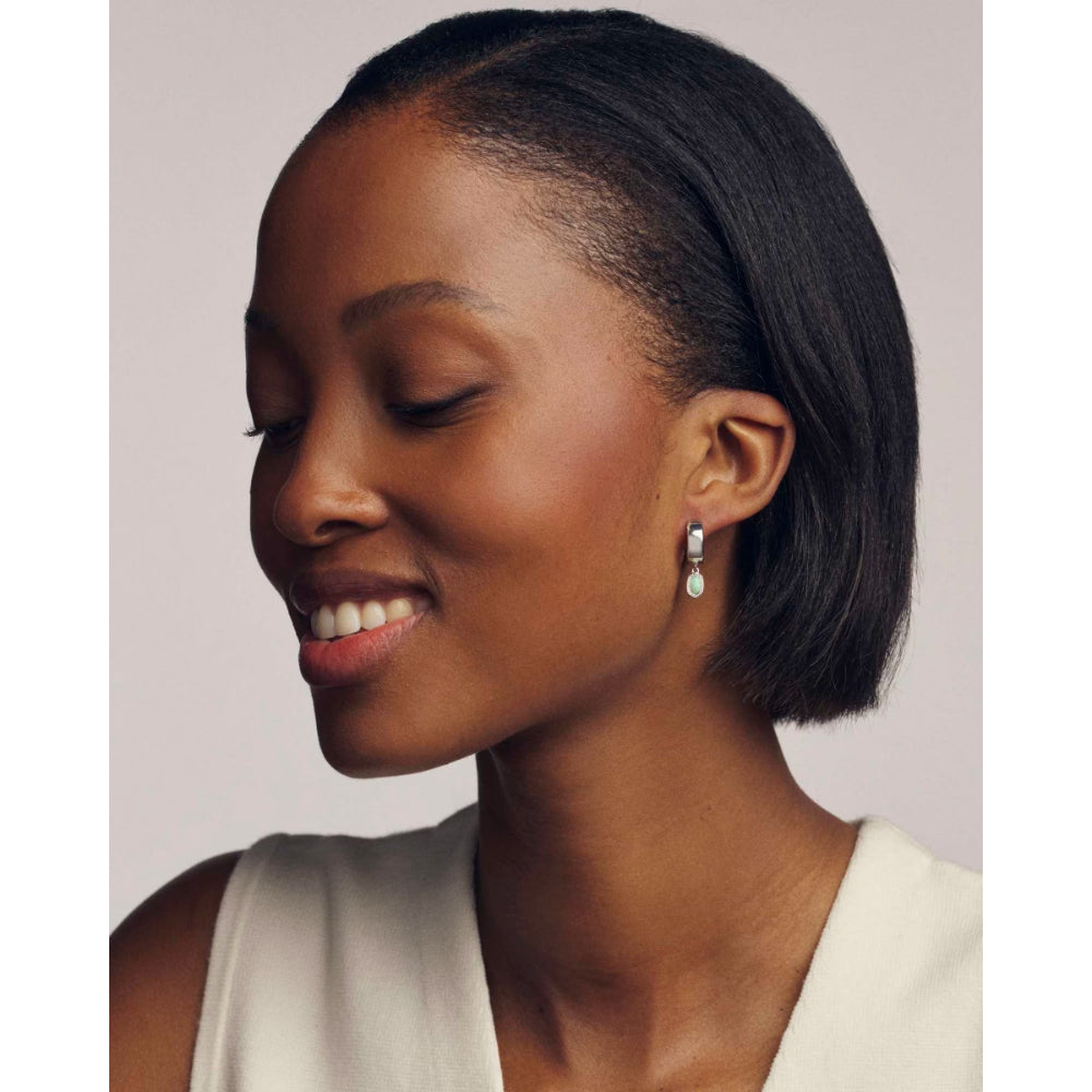 Woman with styled hair wearing earrings against a neutral background