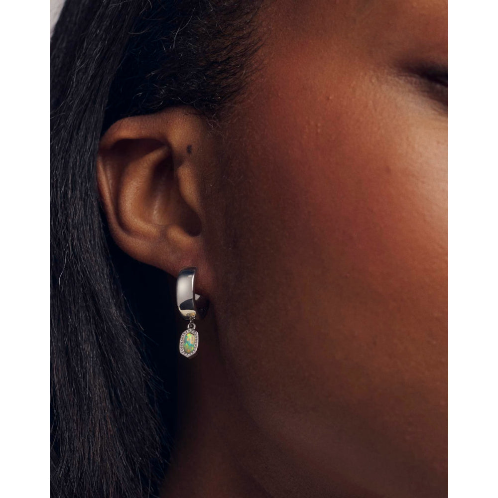 Close-up of an ear wearing a silver earring with a small gemstone.