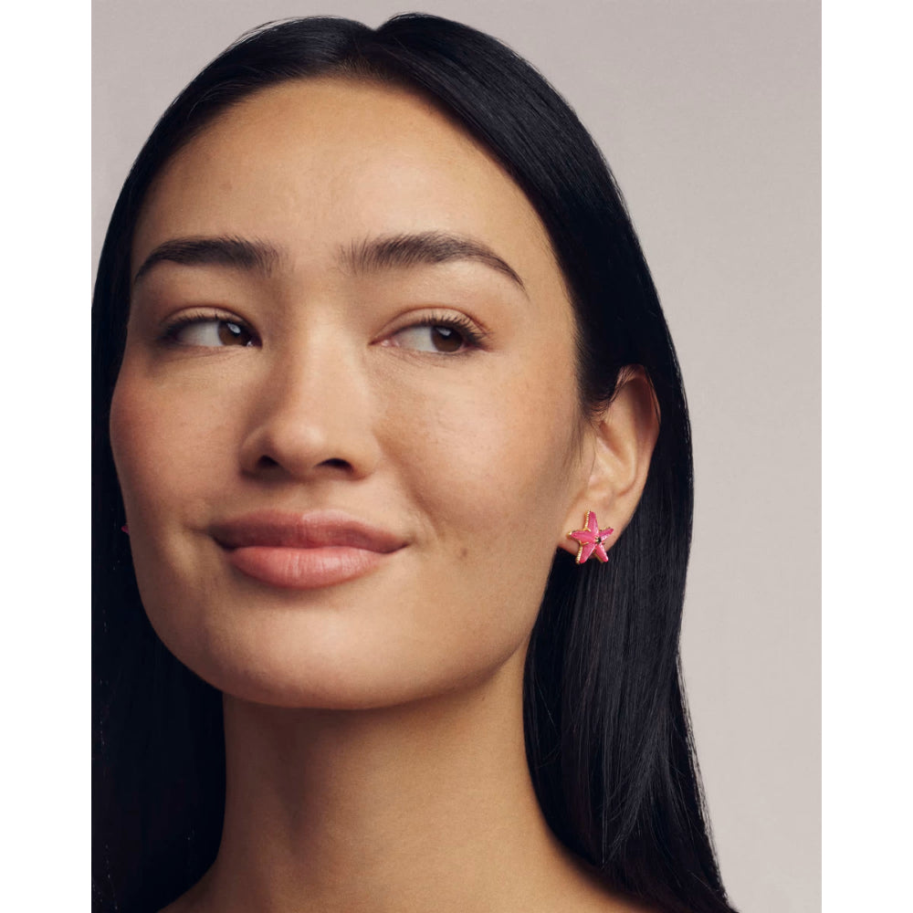 Close-up of a woman wearing pink flower earrings with a neutral background