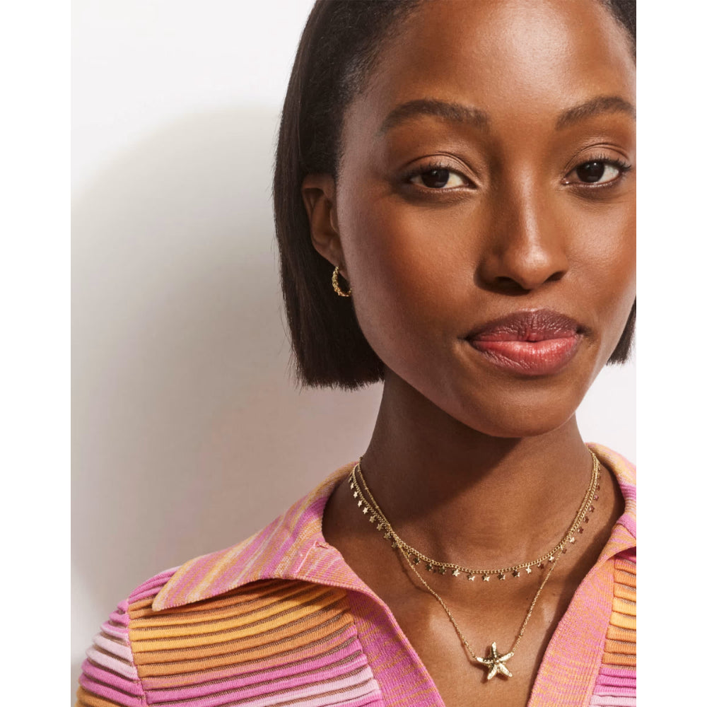 Woman wearing a striped shirt with visible jewelry against a plain background