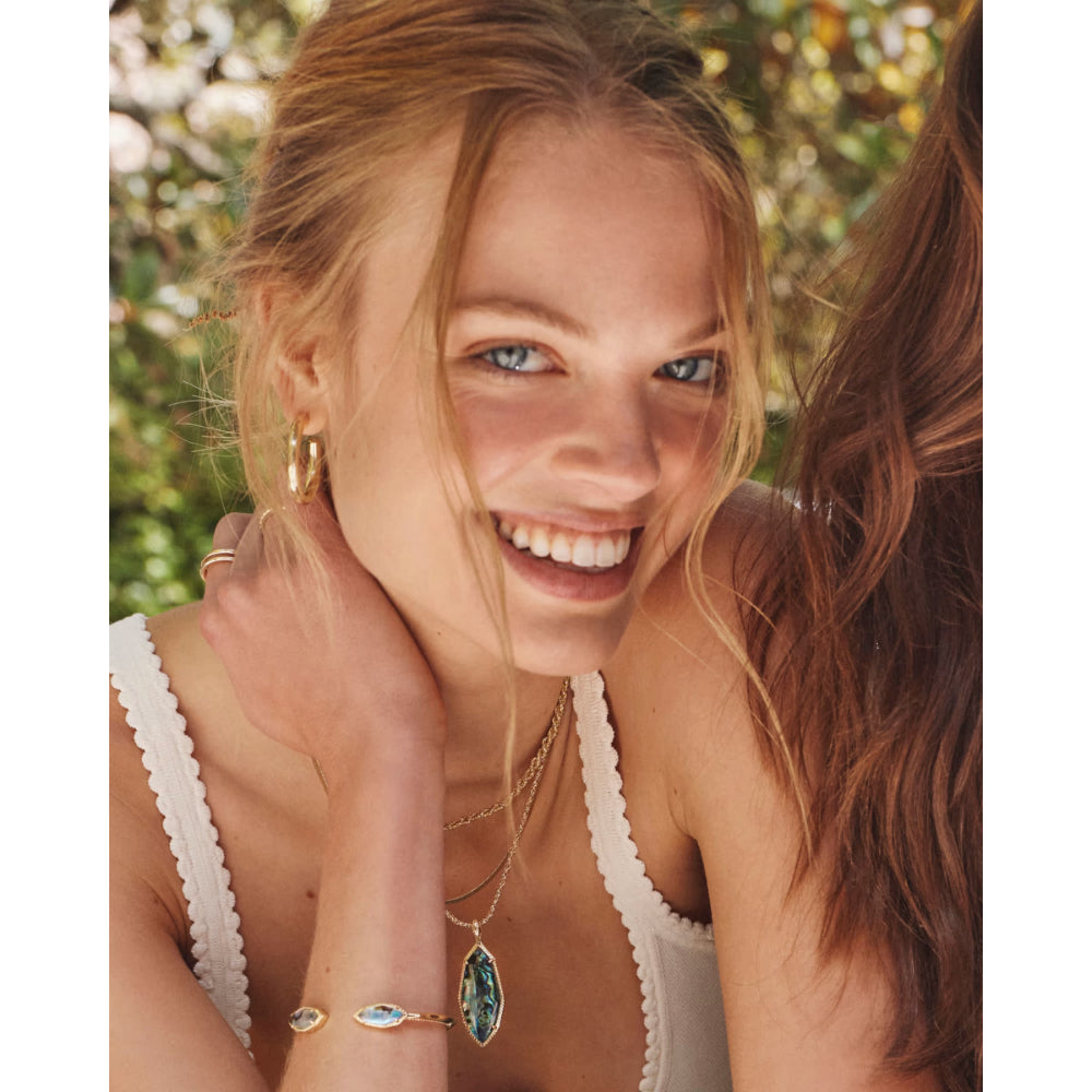Woman with gold jewelry smiling outdoors