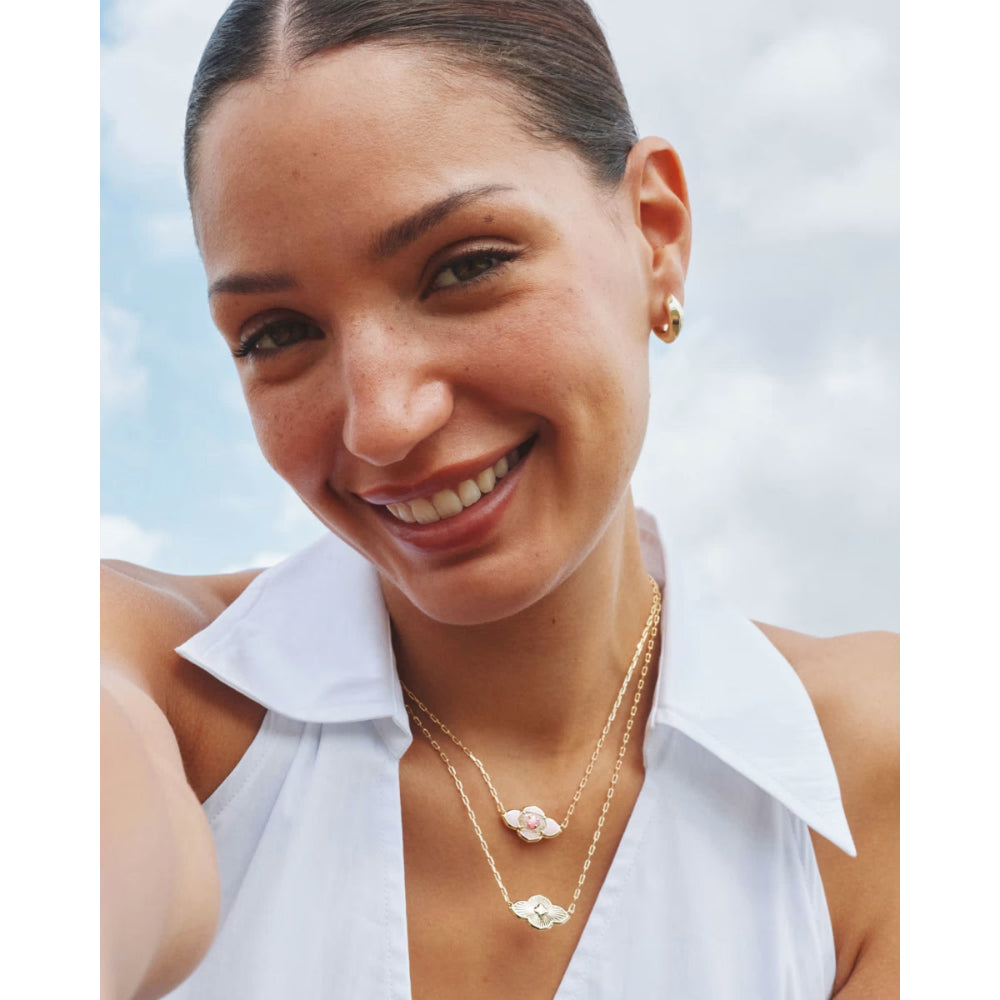 Woman wearing a white sleeveless top and gold necklaces with a blurred background