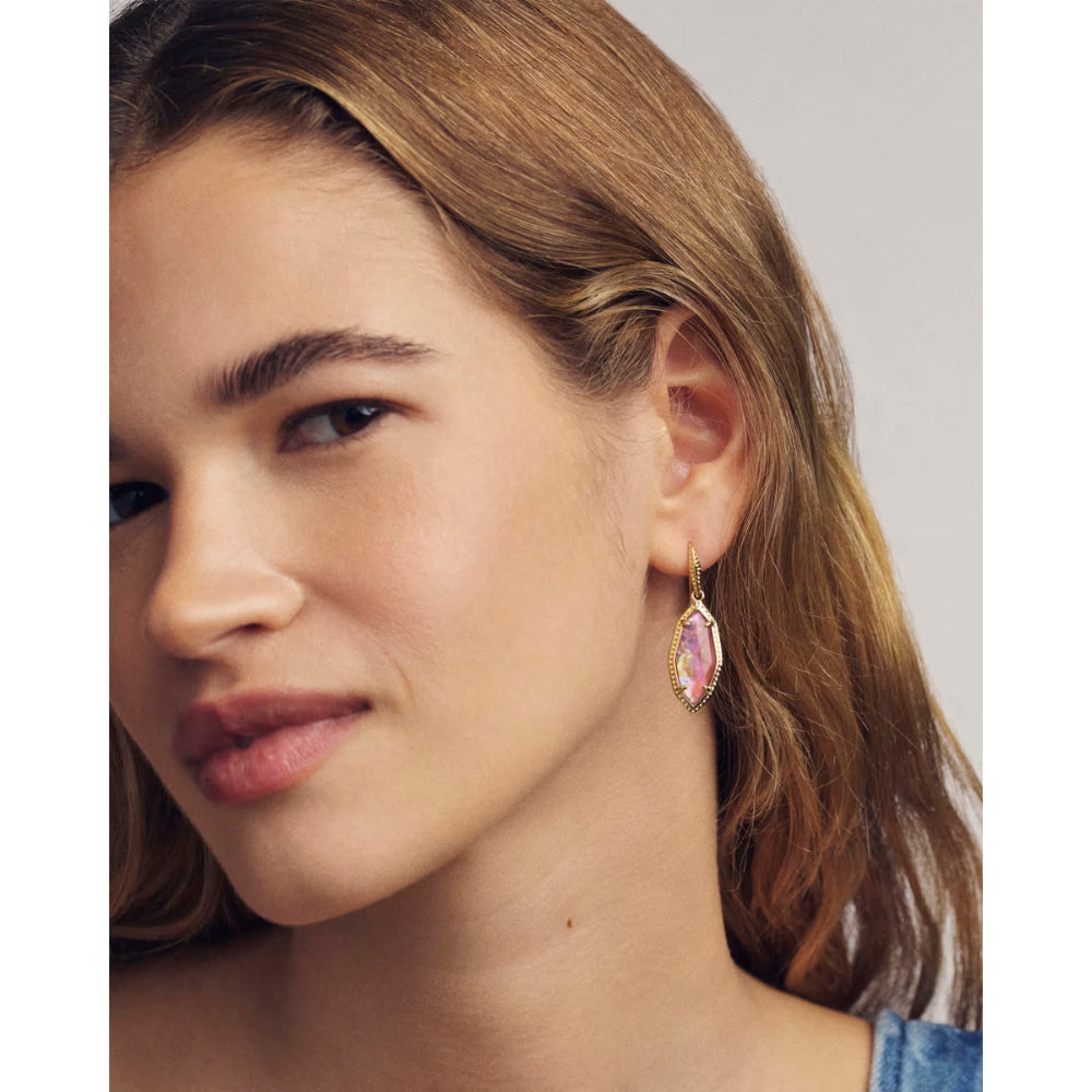Close-up of a woman wearing a pink gemstone earring with a neutral background