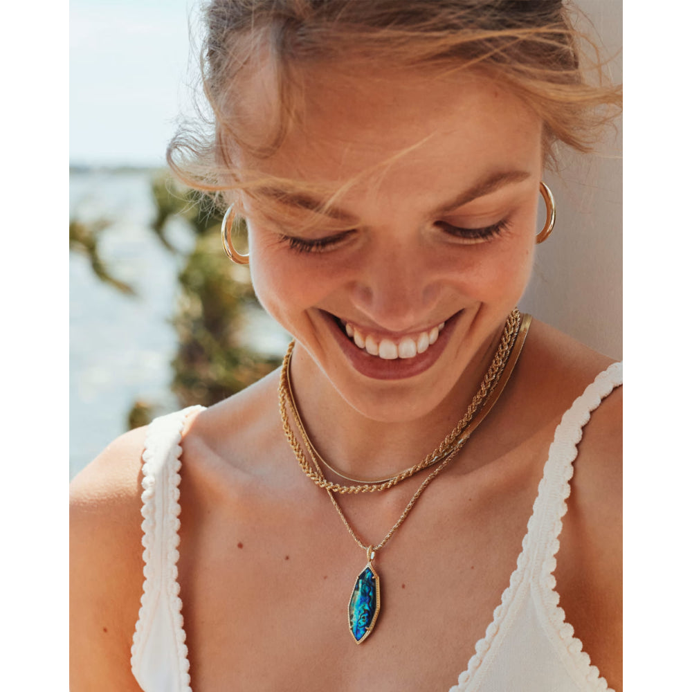 Woman wearing a necklace with a blue pendant outdoors