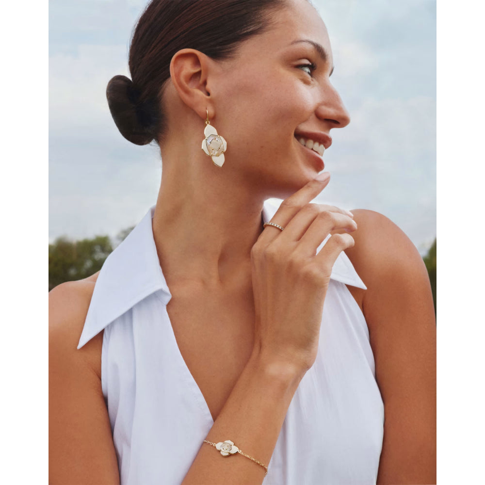 Woman wearing gold earrings and bracelet with a blurred outdoor background