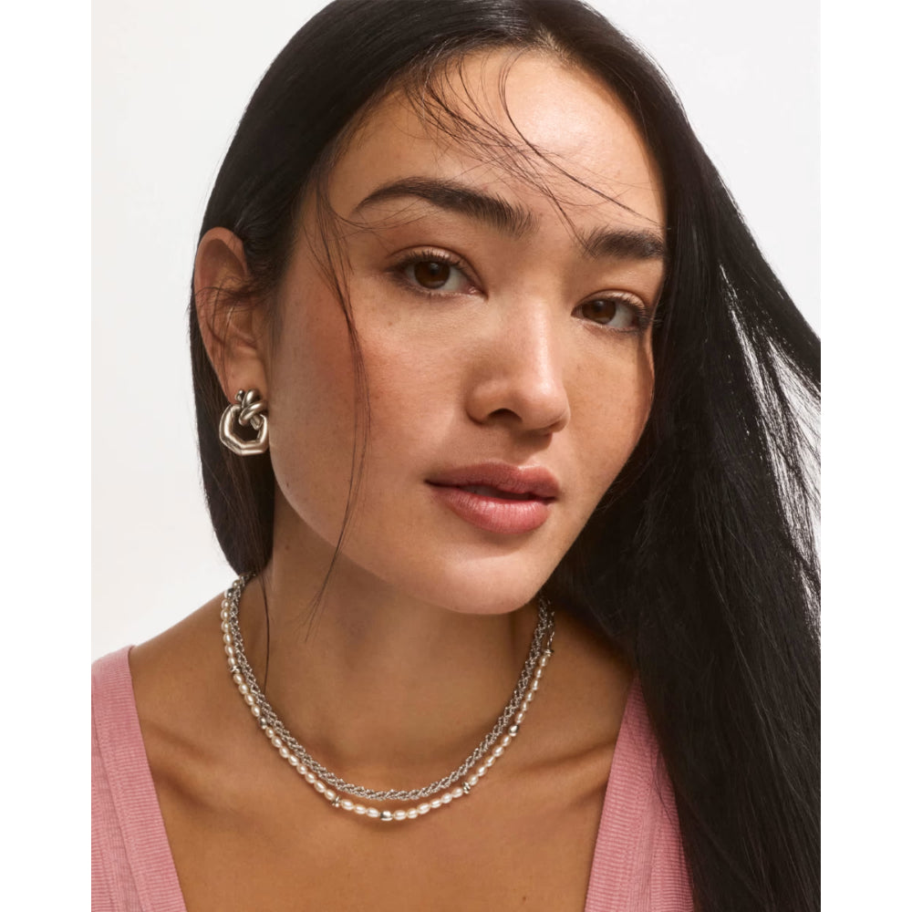 Woman wearing a silver necklace and earrings on a white background