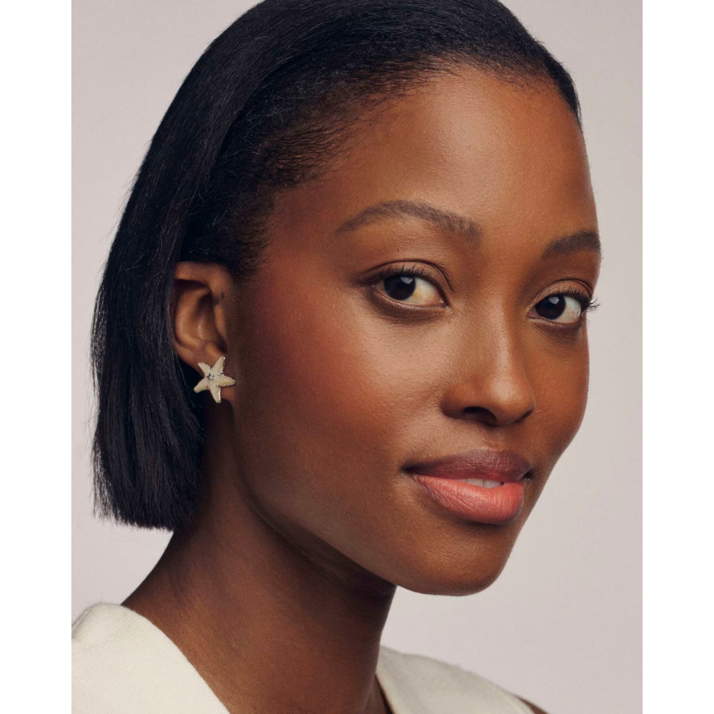 Woman wearing a star-shaped earring against a plain background