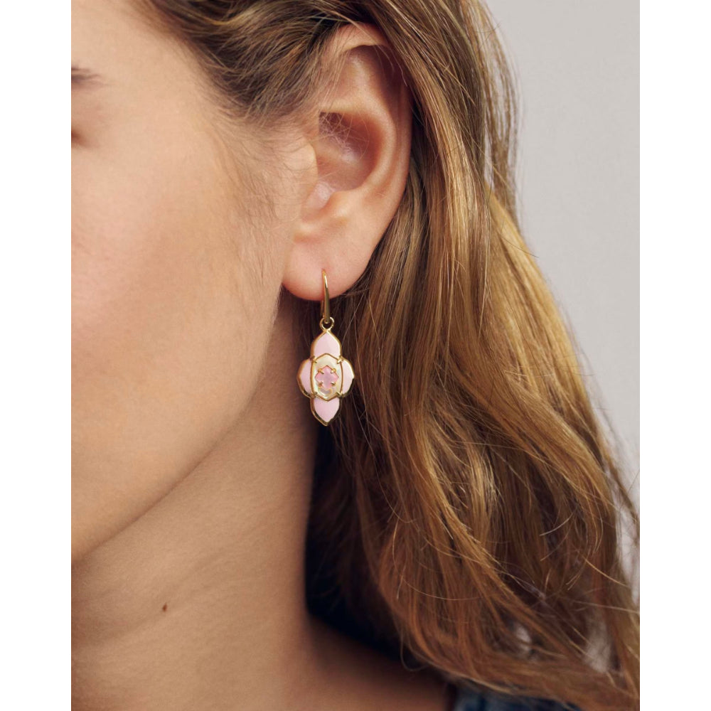 Close-up of a woman wearing earring with a pink gemstone.