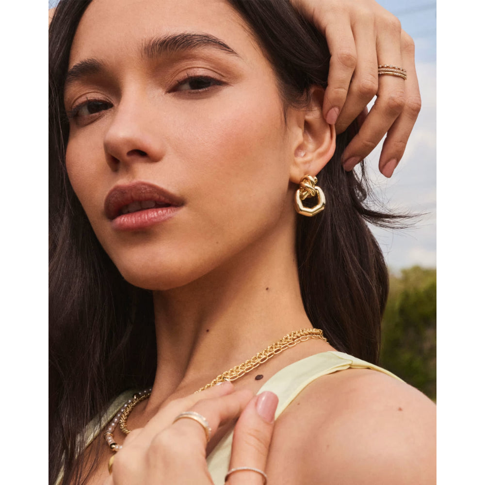 Woman wearing gold jewelry with a blurred outdoor background