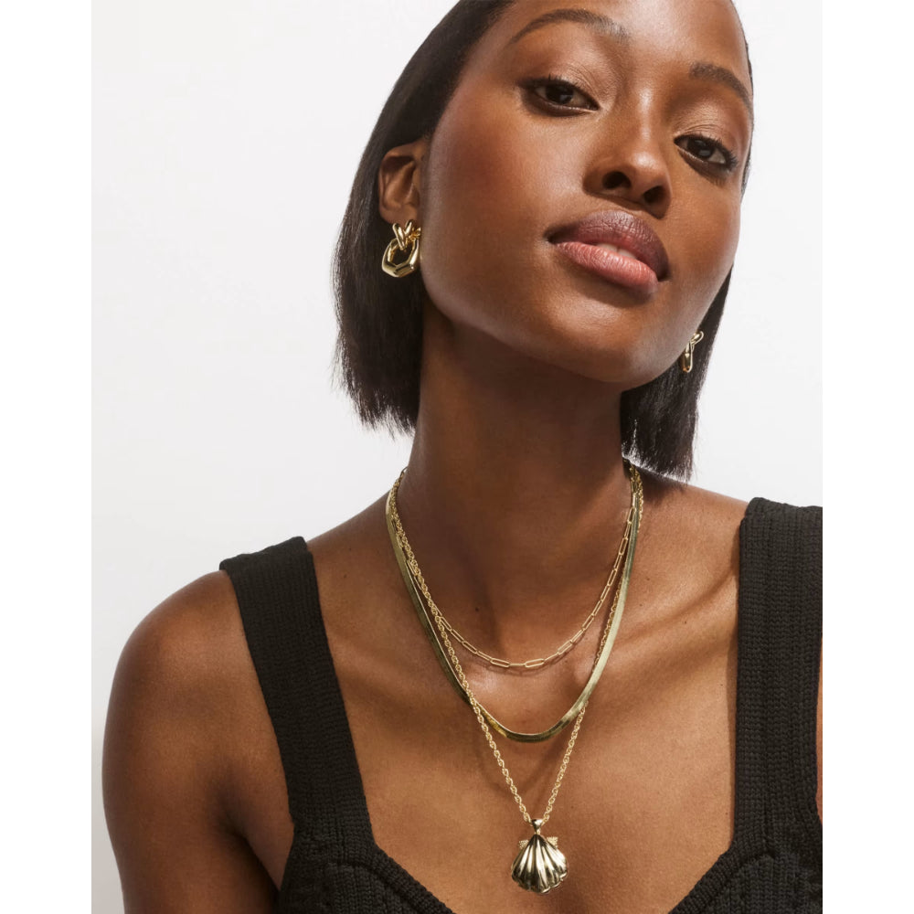 Woman wearing gold necklaces and earrings on a white background